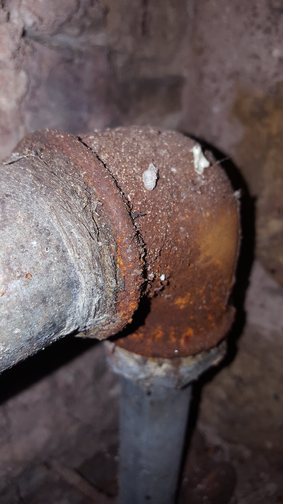 Nahaufnahme eines rostigen Rohrverbindungsteils mit abblätternder Rostschicht.