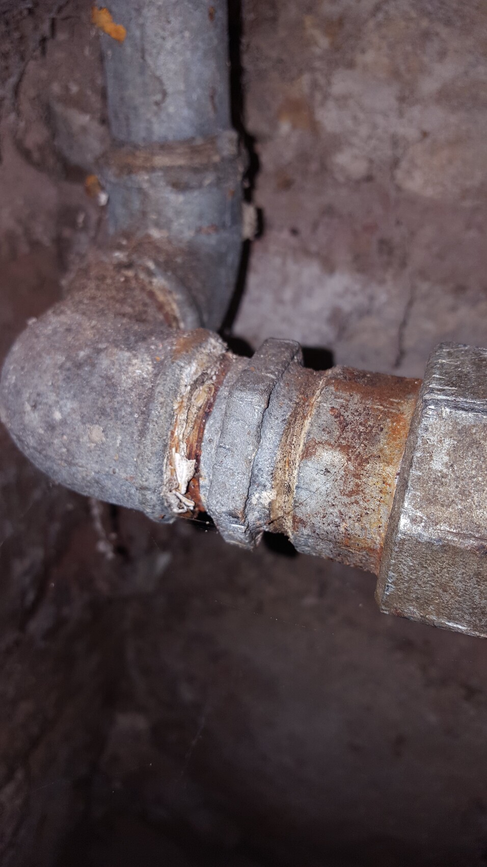 Rostiges Metallrohr mit Biegung und Ablagerungen in dunkler Umgebung