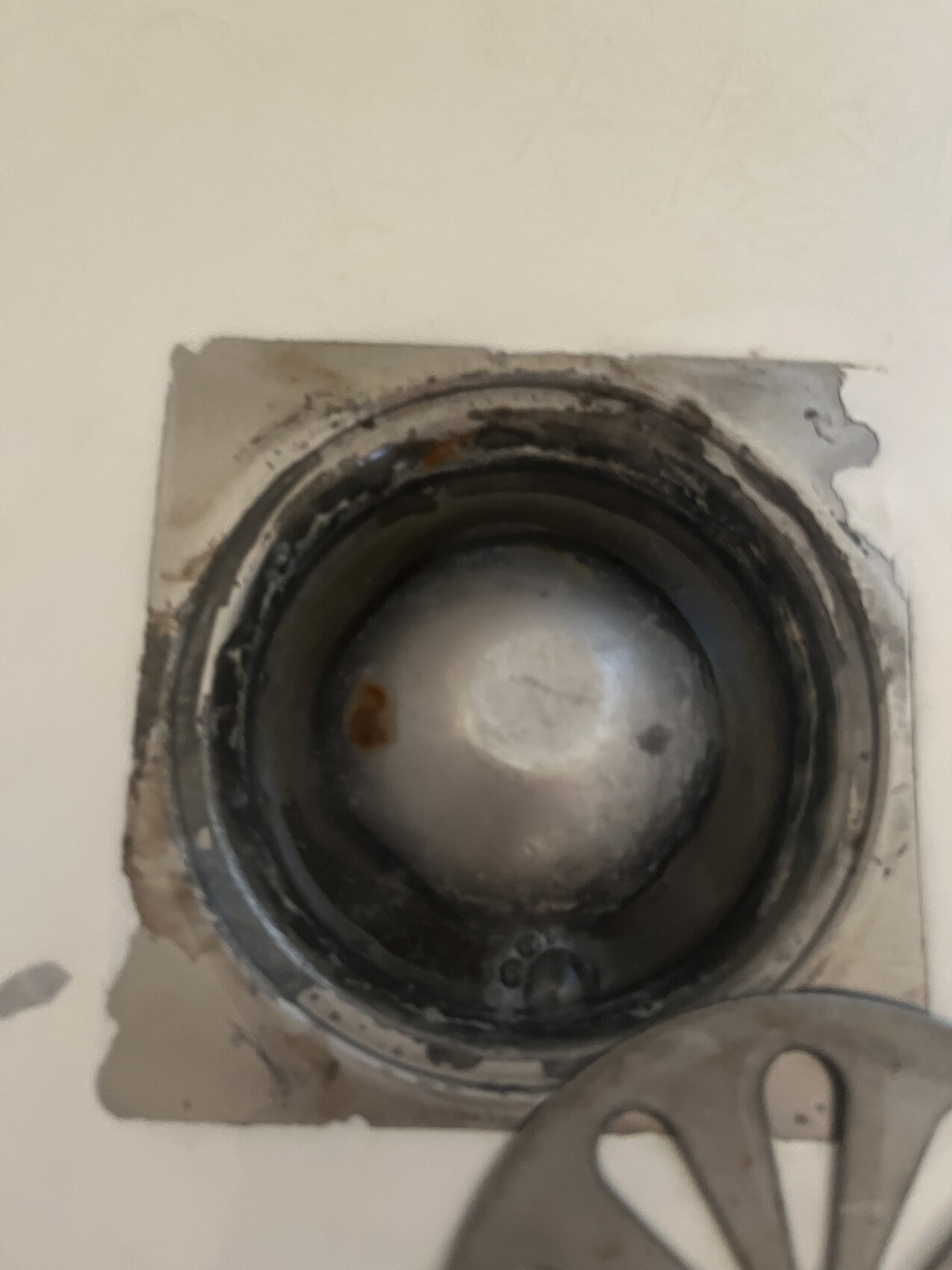 Offene Wandöffnung mit rundem Metallteil, dunkler Innenraum, verschmutzte Dichtung.