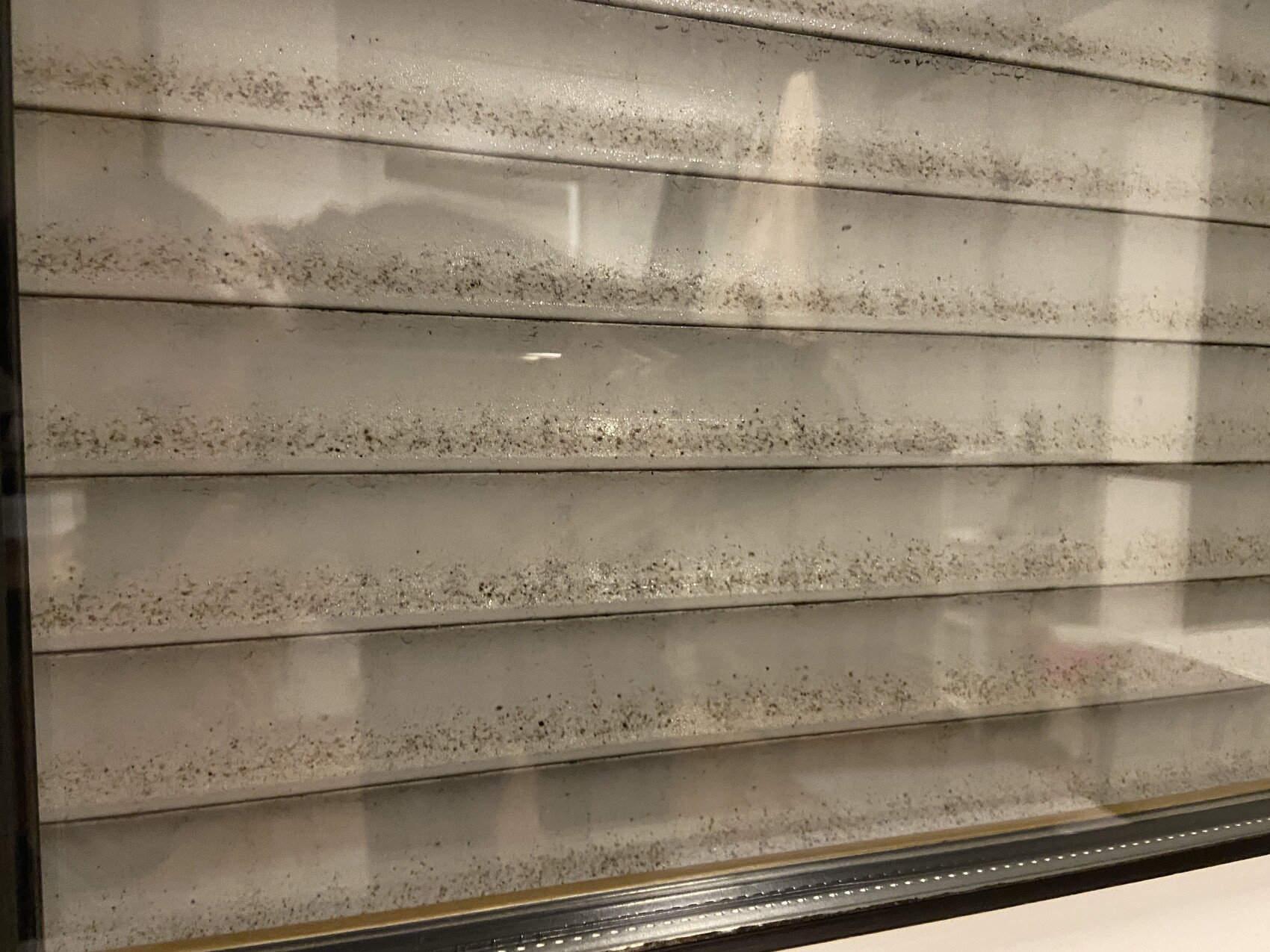 Schmutzige horizontale Rolladen an Fenster mit Staub und Flecken