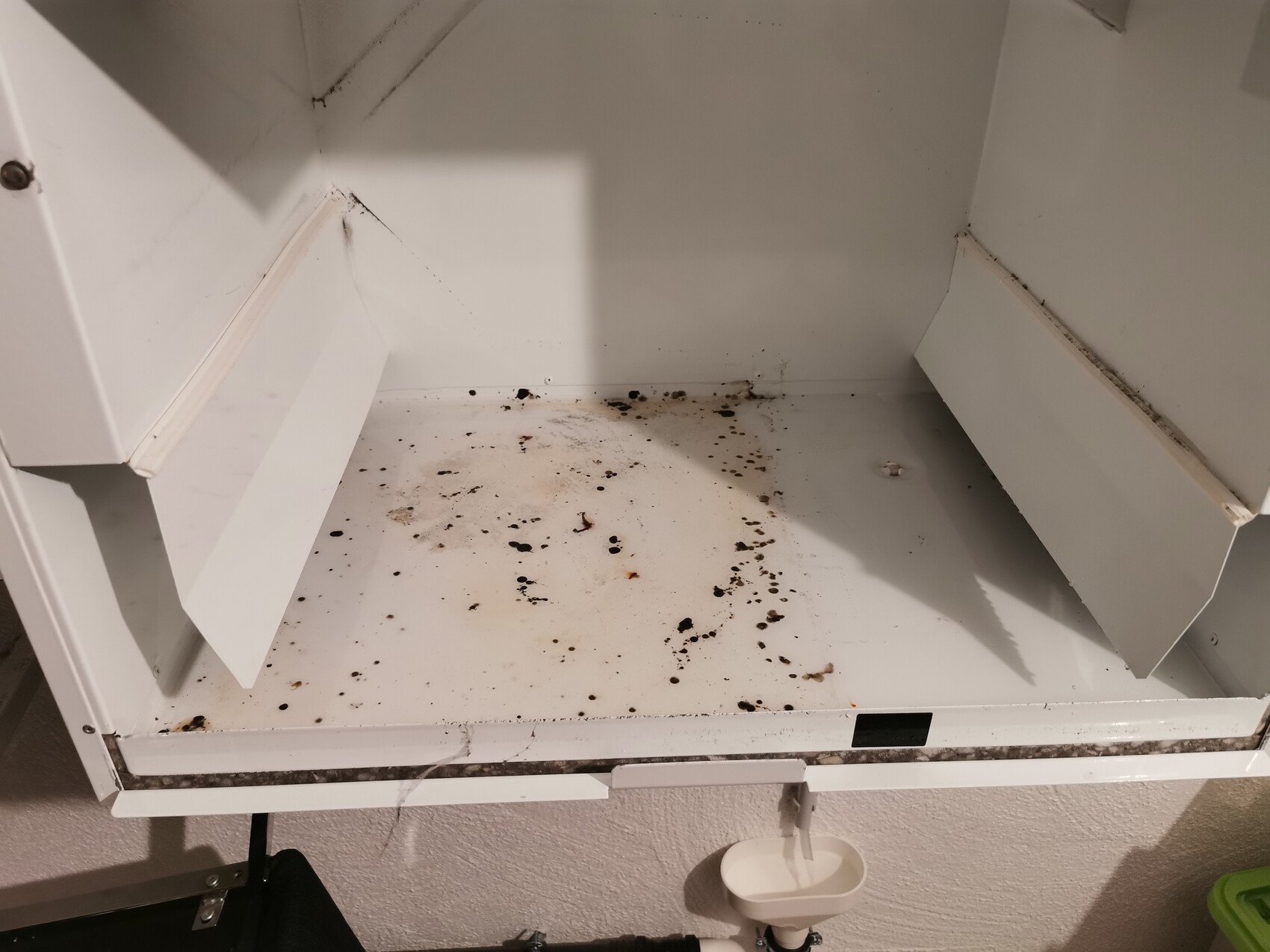 Offener weißer Küchenschrankboden mit schwarzen Flecken und Schmutz