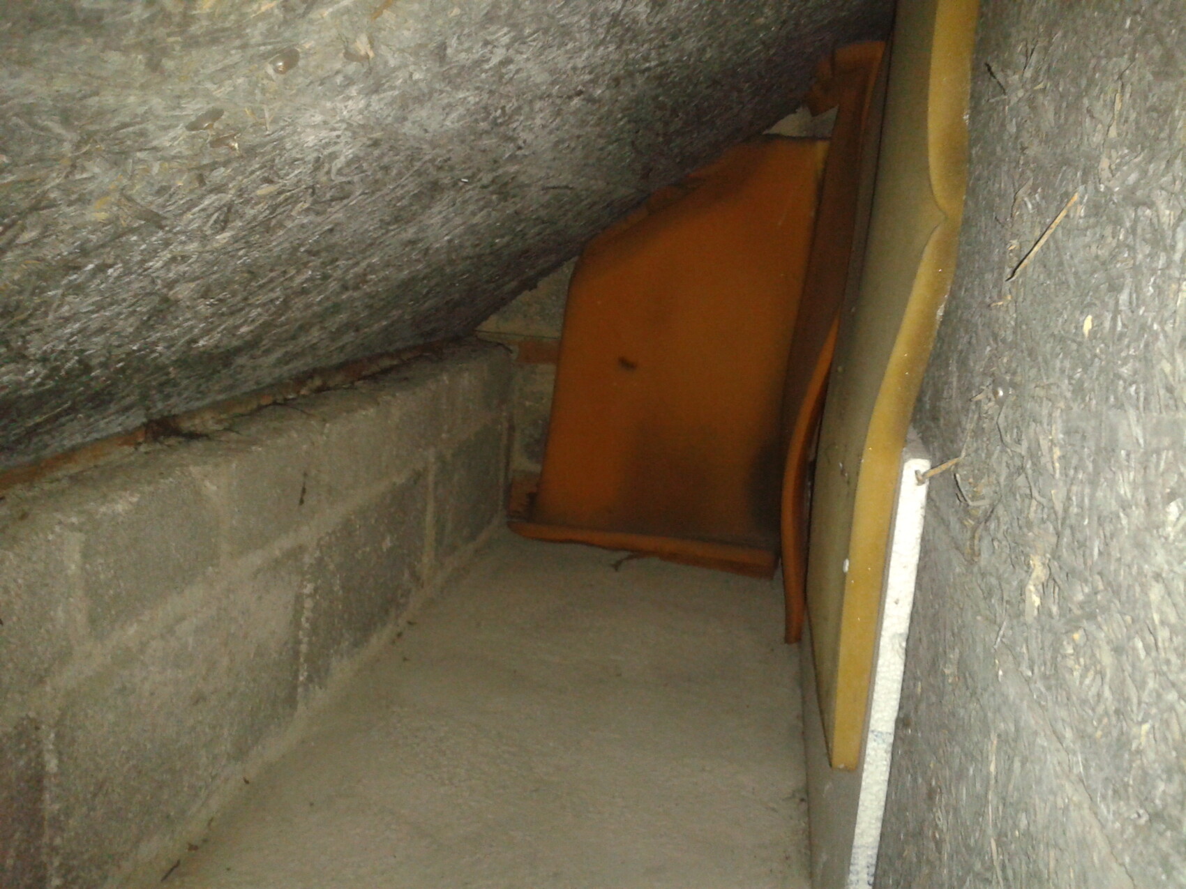 Enge Dachbodenecke mit orangefarbener Sitzbank, zwischen Wand und schräger Decke