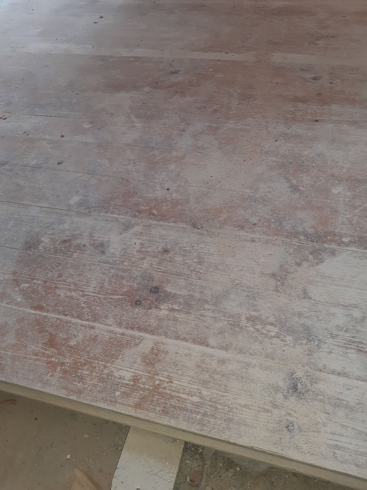 Holzoberfläche mit abgeplatzter, staubiger Lackschicht in braun-ocker Tönen.