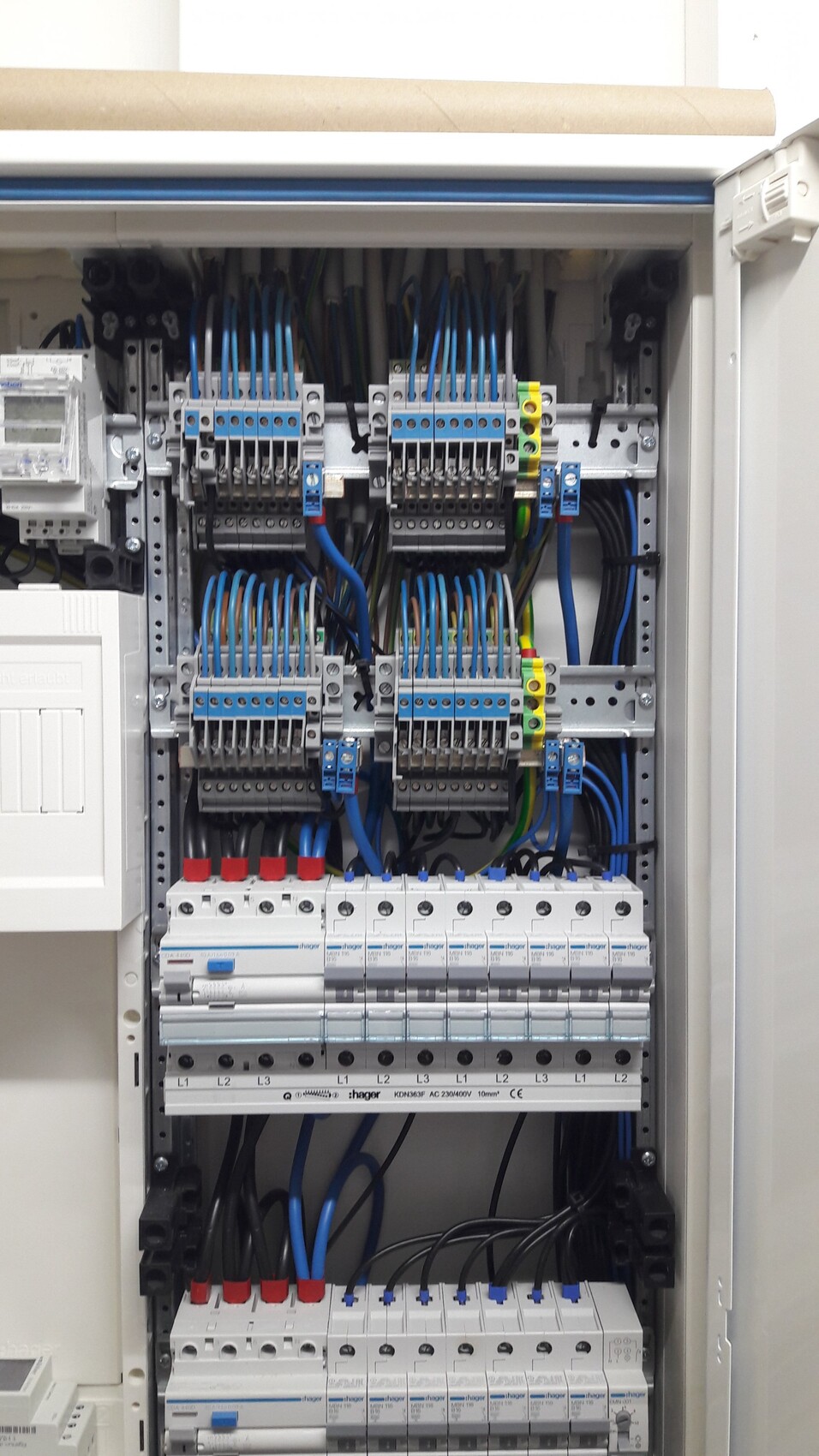 Elektrische Schalttafel mit vielen blauen Leitungen, Klemmenleisten und Sicherungen