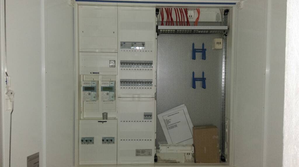 Verteilerschrank mit Sicherungskästen, Kabeln und Montageplatte in einem Haustechnikraum