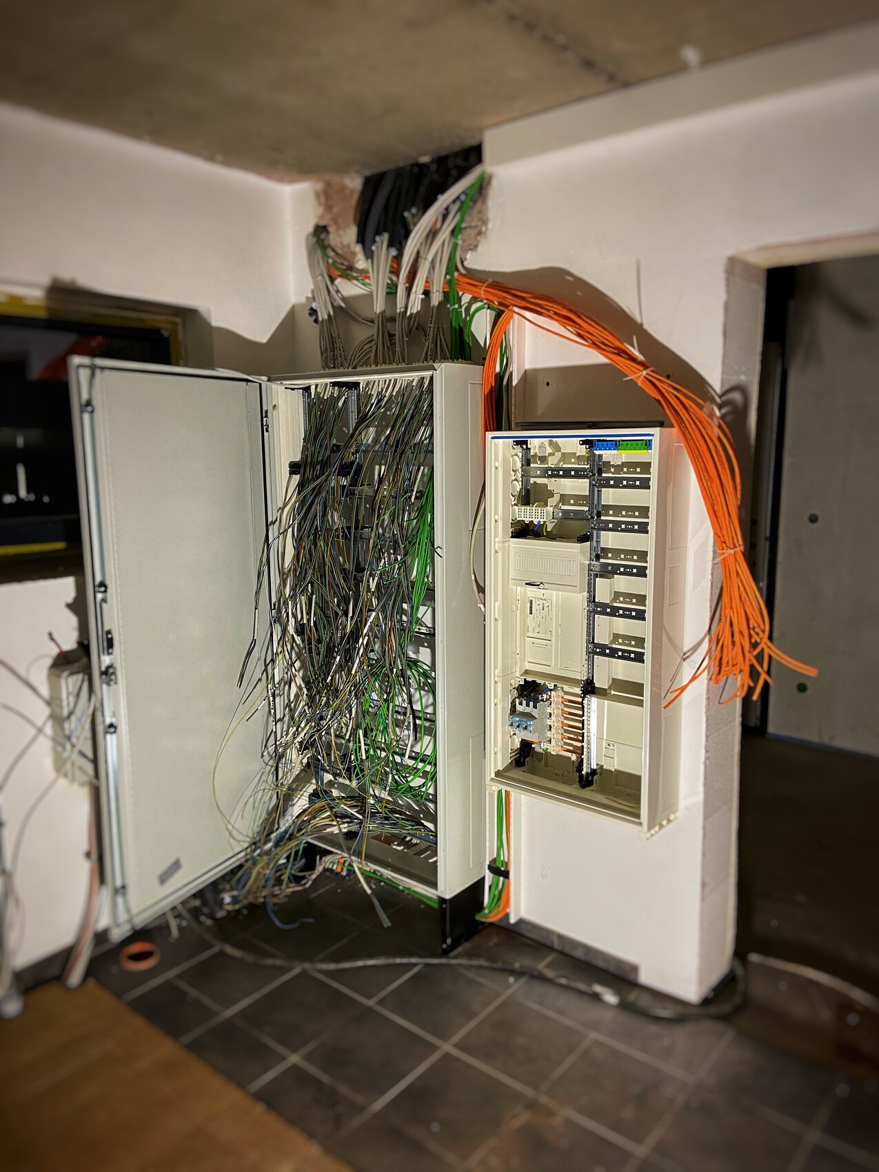 Offener Netzwerkschrank mit vielen Kabelbündeln (grün/orange) und Patchpanel.