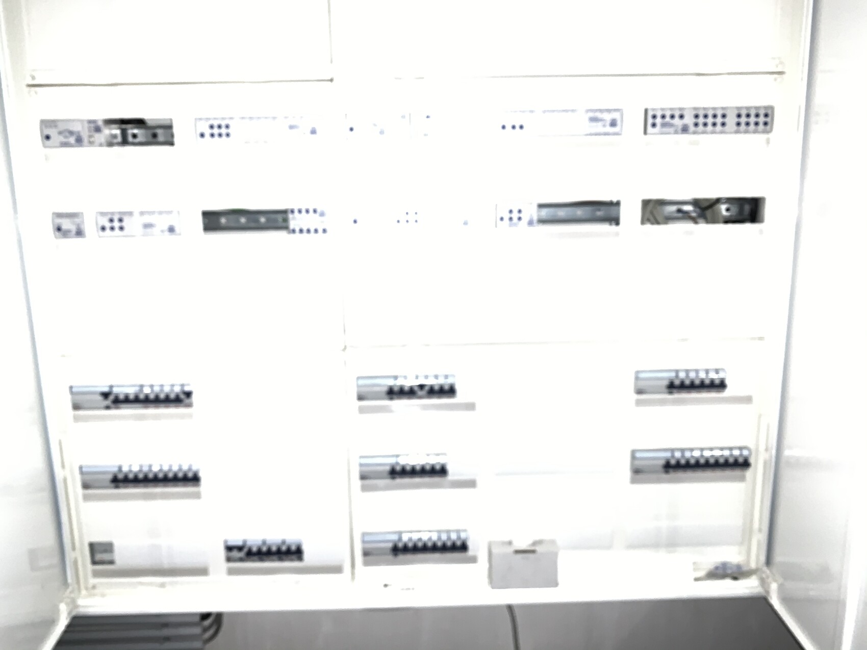 Weißer elektrischer Schaltschrank mit mehreren Sicherungsmodulen auf DIN-Schienen.