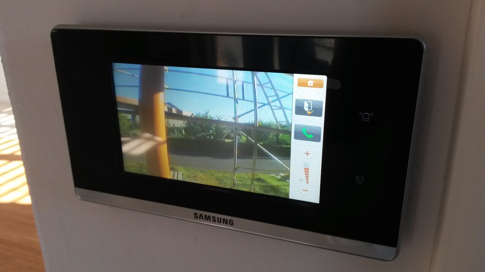 Samsung-Video-Türsprechanlage: Monitor zeigt Außenbereich mit Geländer und Garten.
