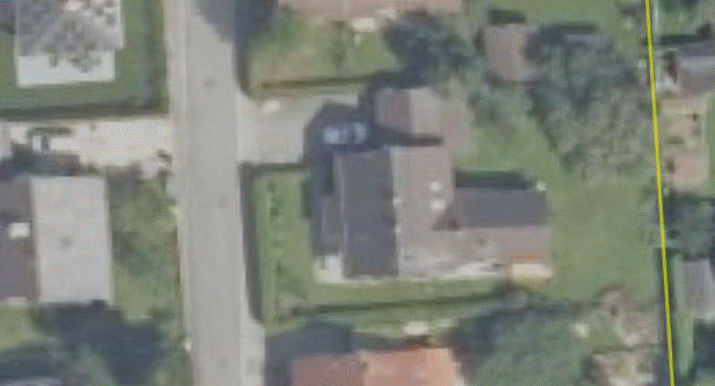 Luftaufnahme eines Wohnviertels mit Häusern, Gärten und Straßen; rechte Gelb-Grenze sichtbar.