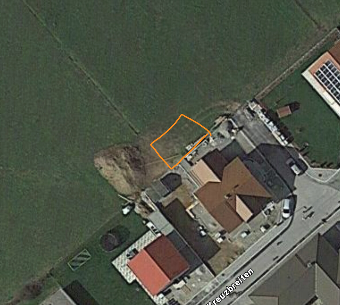 Luftbild eines Hauses; orange Umrandung markiert eine kleine Rasenfläche hinter dem Haus.