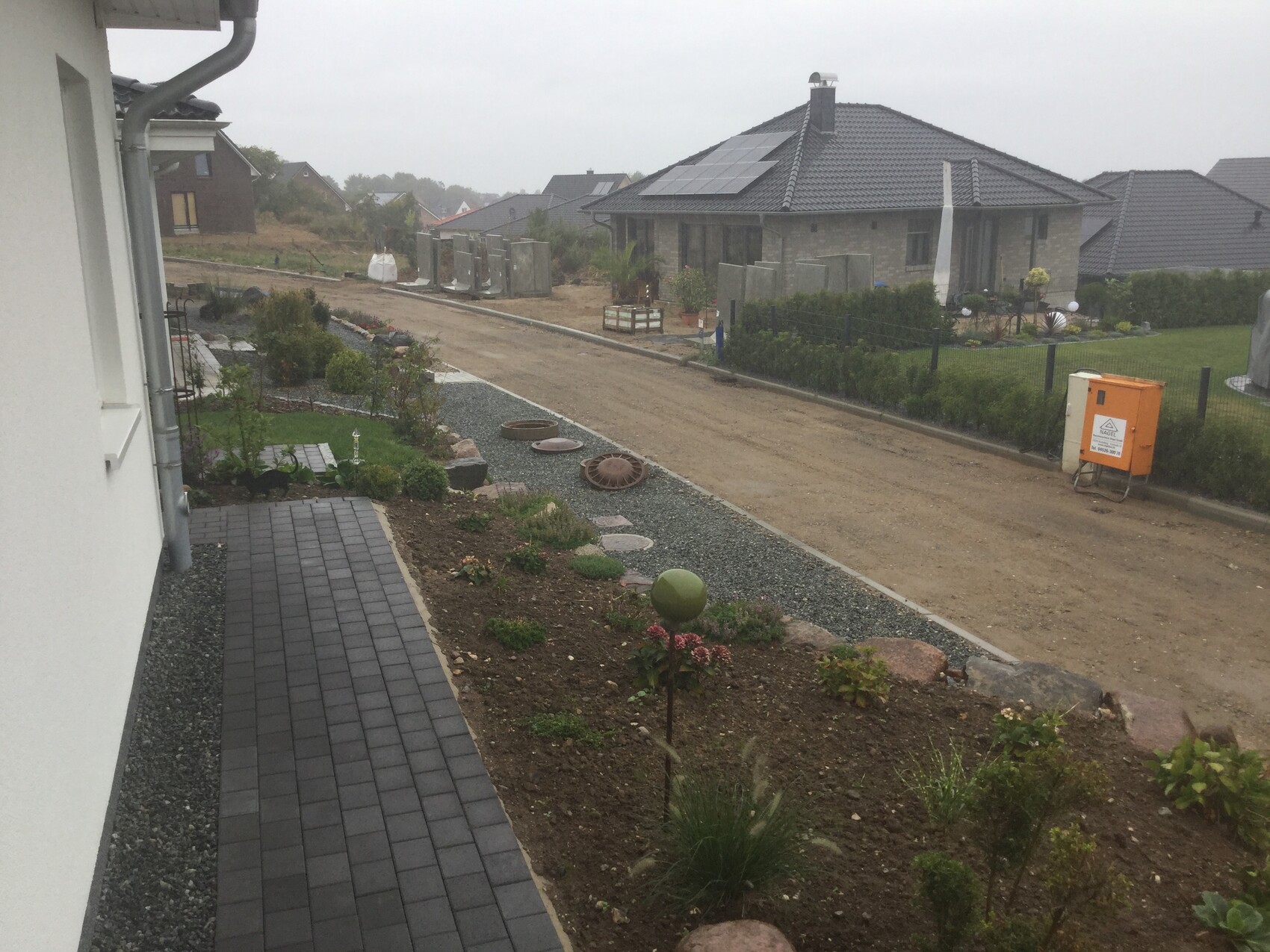 Vordergarten mit Kiesweg, Beeten und Bauarbeiten vor Neubauhaus