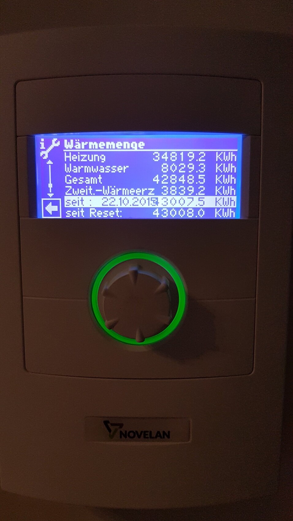 NOVELAN Heizungsregler mit blauem Display und grünem Ring um den Drehknopf.