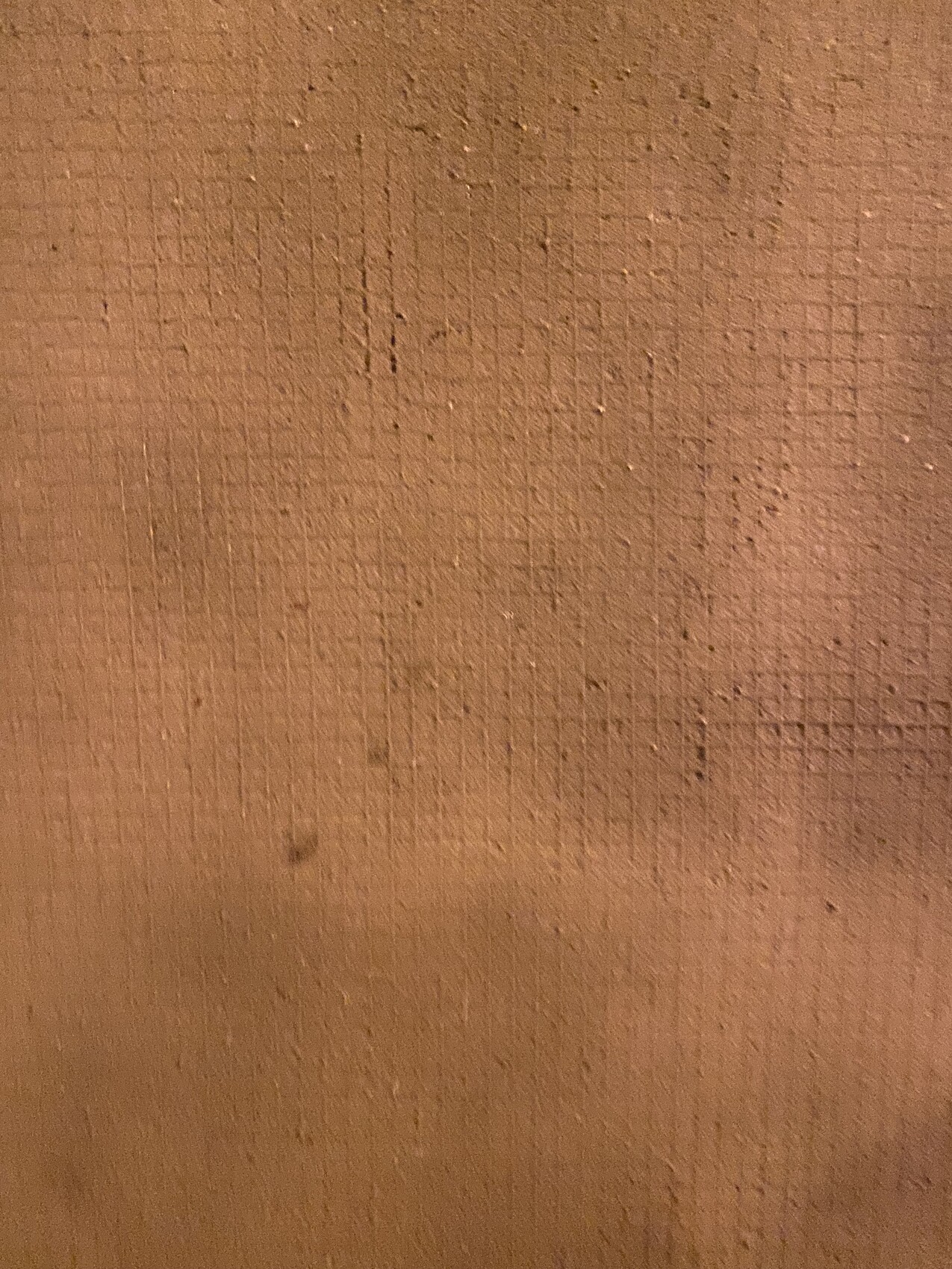 Nahaufnahme einer braunen Wandoberflaeche mit Putzstruktur und Rillen