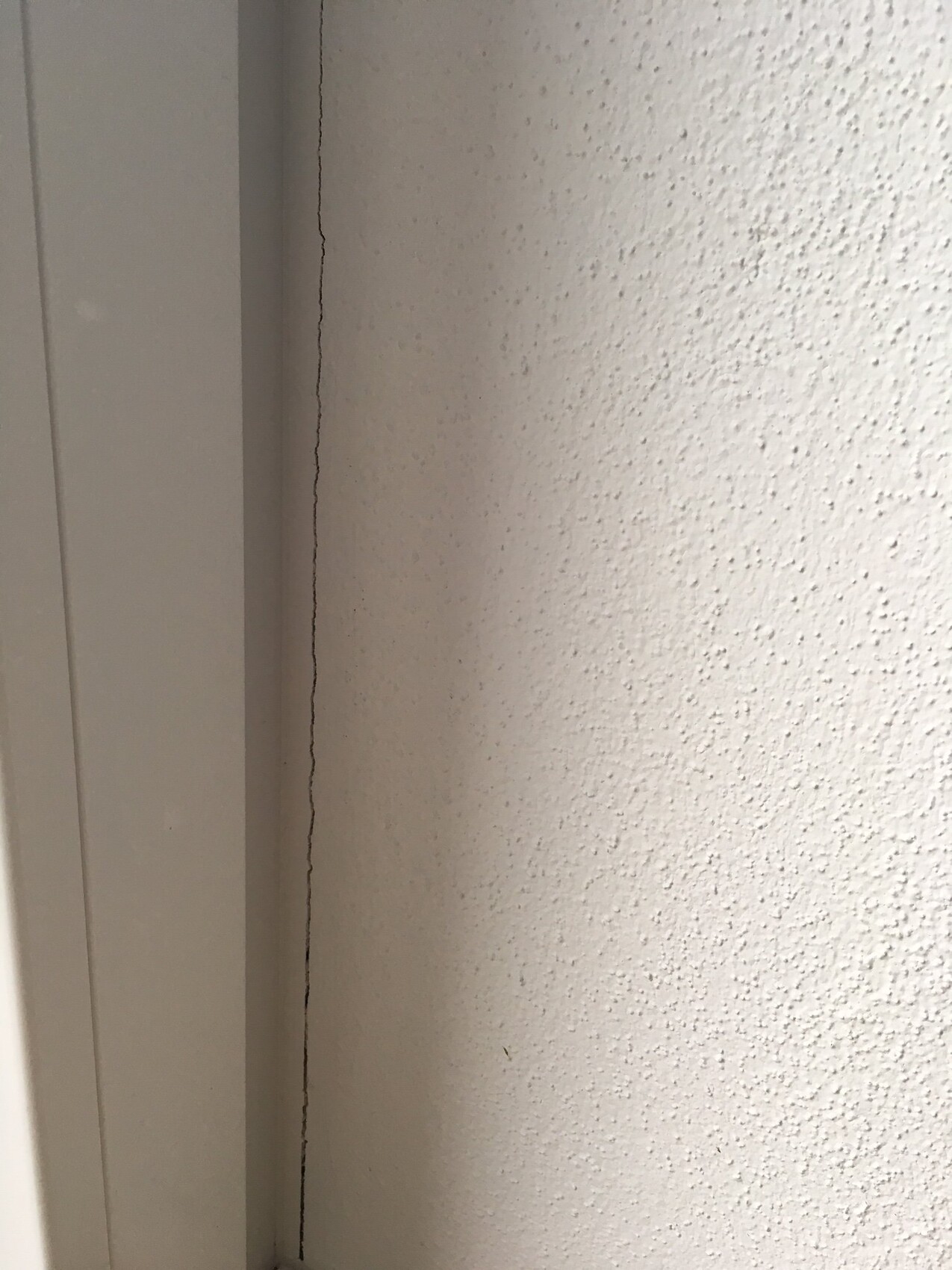 Feiner Riss in der Wand neben dem Türrahmen, Hinweis auf Baumangel