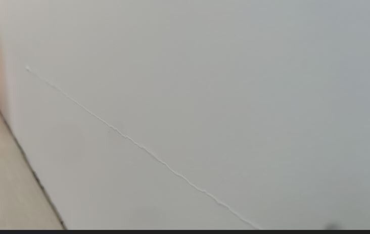 Diagonal er Riss in einer weißen Wand, Hinweis auf Baumängel.