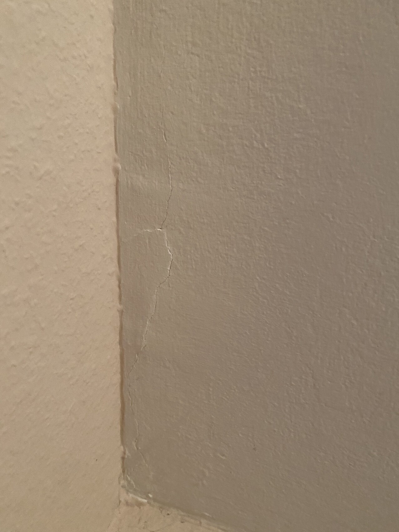 Nahaufnahme einer Innenwand-Ecke mit feinem Riss im Putz entlang der Kante.