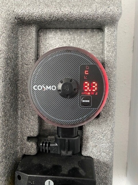 Rundes COSMO-Messgerät mit roter LED-Anzeige an Betonblock, Kabelanschluss unten.