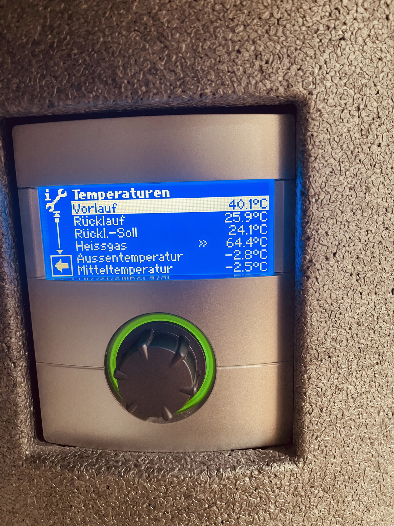 Anzeige eines Heizungsreglers mit Temperaturwerten und grünem Einstellrad