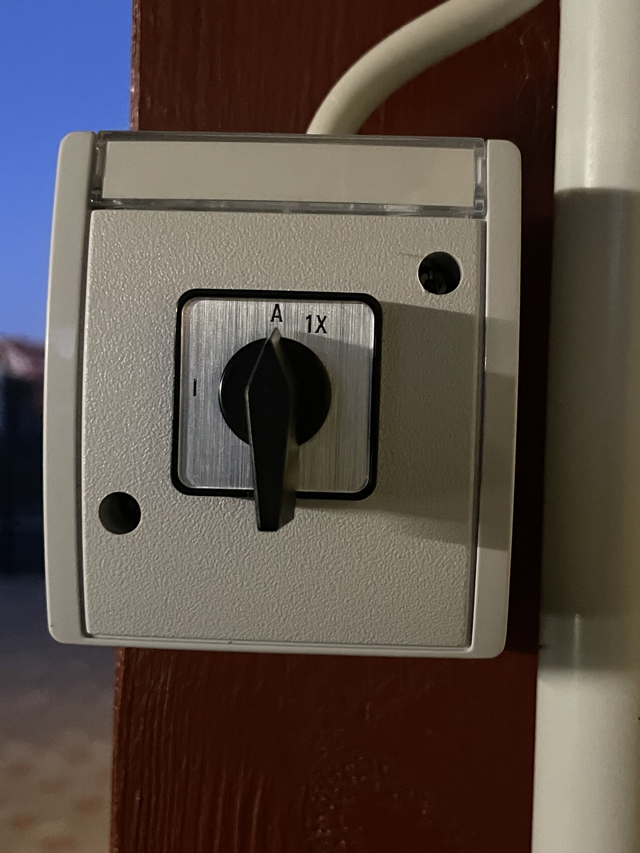 Elektrischer Drehschalter mit schwarzem Hebel im silbernen Metallgehäuse auf Holz, A 1X beschriftet.
