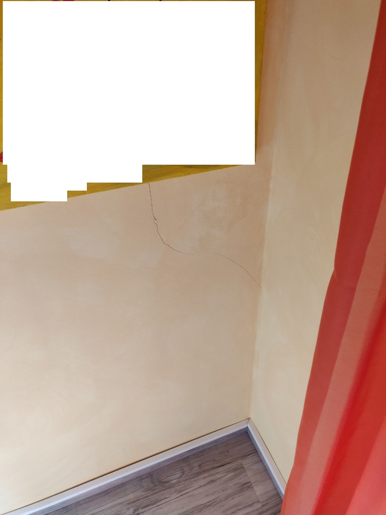 Eckraum mit gelber Wand, sichtbarem Riss, Holzboden; roter Vorhang rechts, großes weißes Rechteck verdeckt.