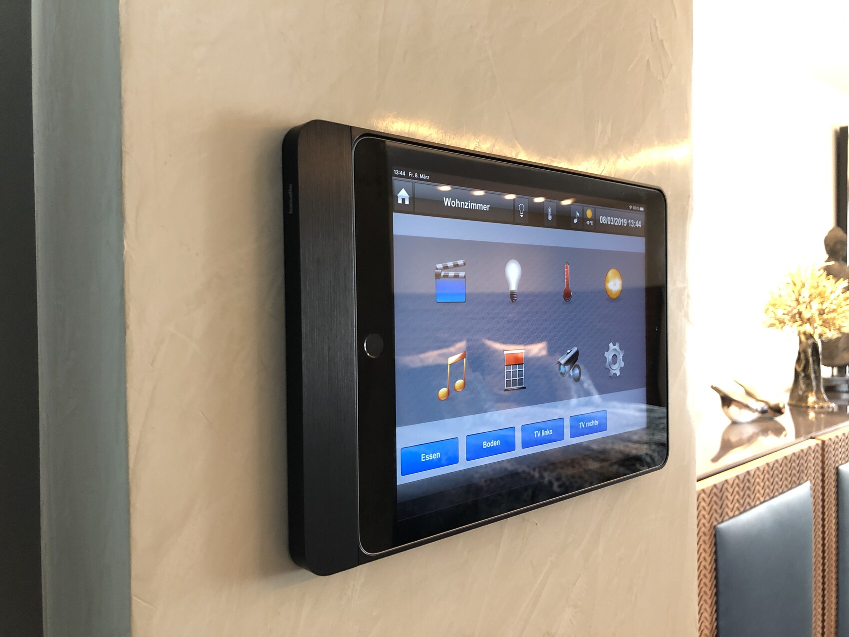 Wandtablet mit Wohnzimmer-Steuerung, Icons für Licht, Musik, Thermostat, TV.