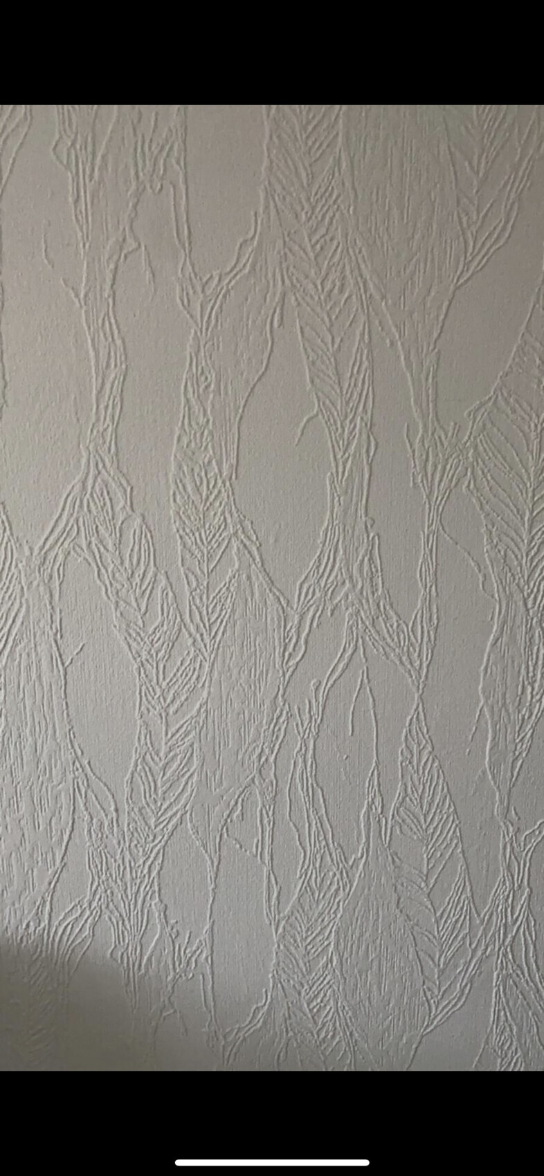 Nahaufnahme einer geprägten Wandtapete mit organischem Baumranken-Muster in Creme.
