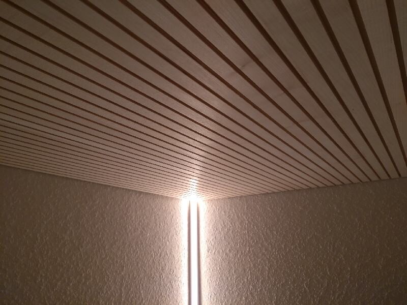 Eckraum mit Holzbalkendecke und vertikaler Lichtleiste an der Ecke.