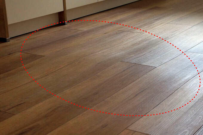 Holzboden im Innenraum; eine ovale rote gepunktete Ellipse markiert einen Bereich.