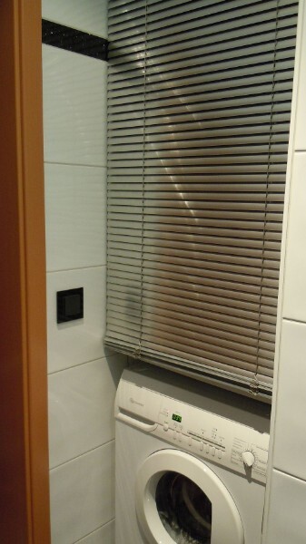 Waschmaschine im Badezimmer neben Fenster mit horizontalen Jalousien