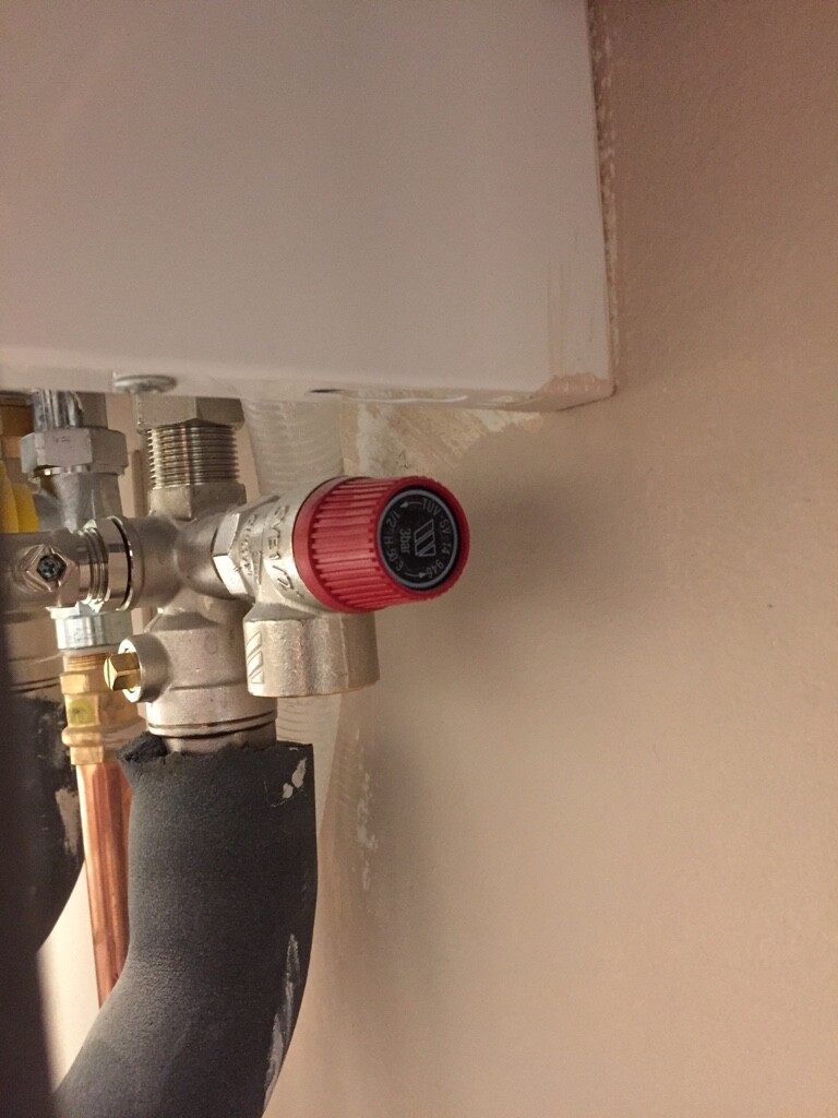 Nahaufnahme eines Wasserabsperrventils mit rotem Griff in einer Sanitärinstallation.