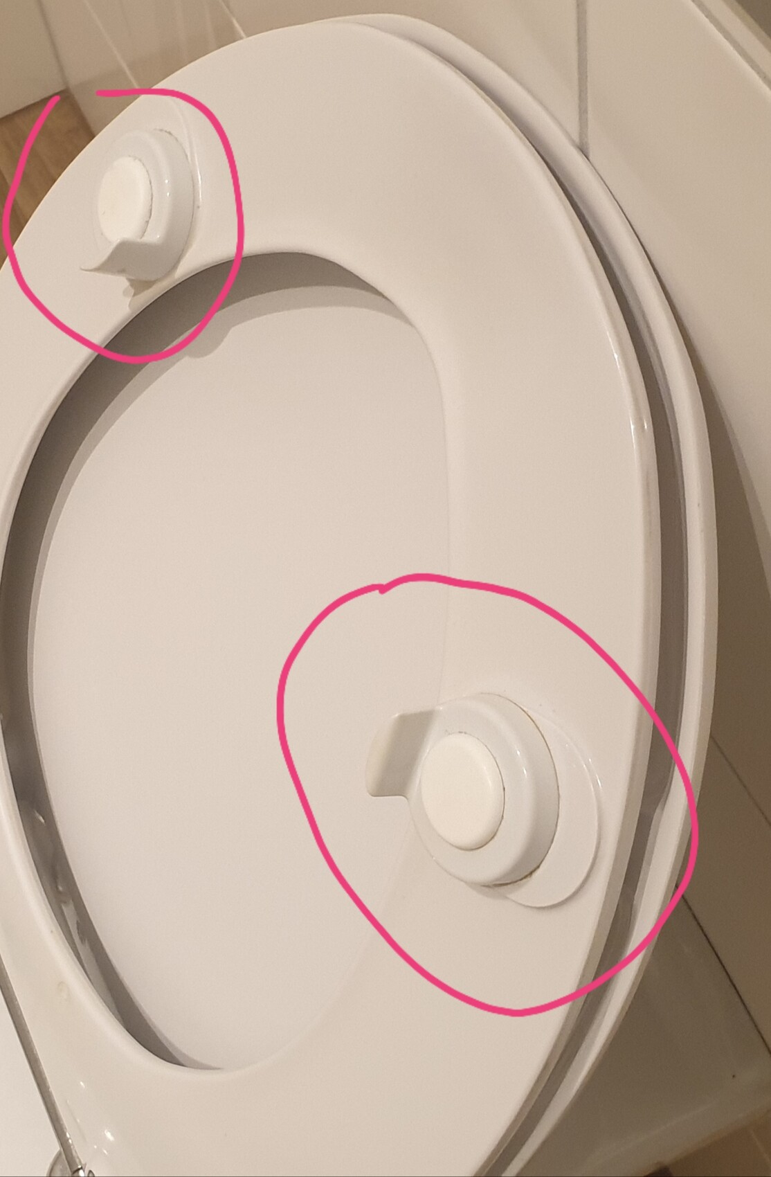 Nahaufnahme eines WC-Sitzes mit Montagekappen am Rand