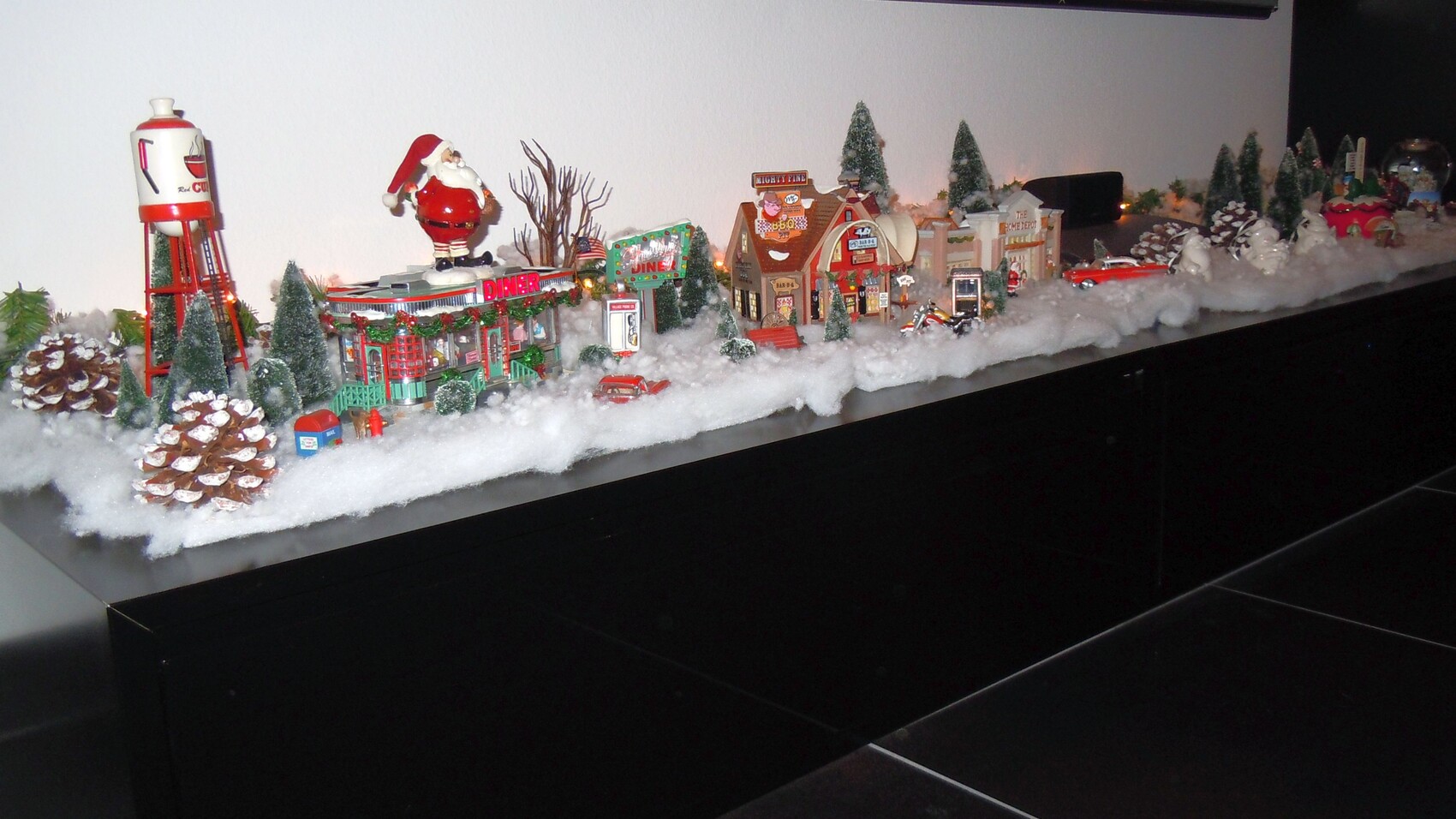 Weihnachtliches Hausmodell-Diorama mit verschneiter Landschaft, kleinen Häusern, Tannen und Santa-Figur