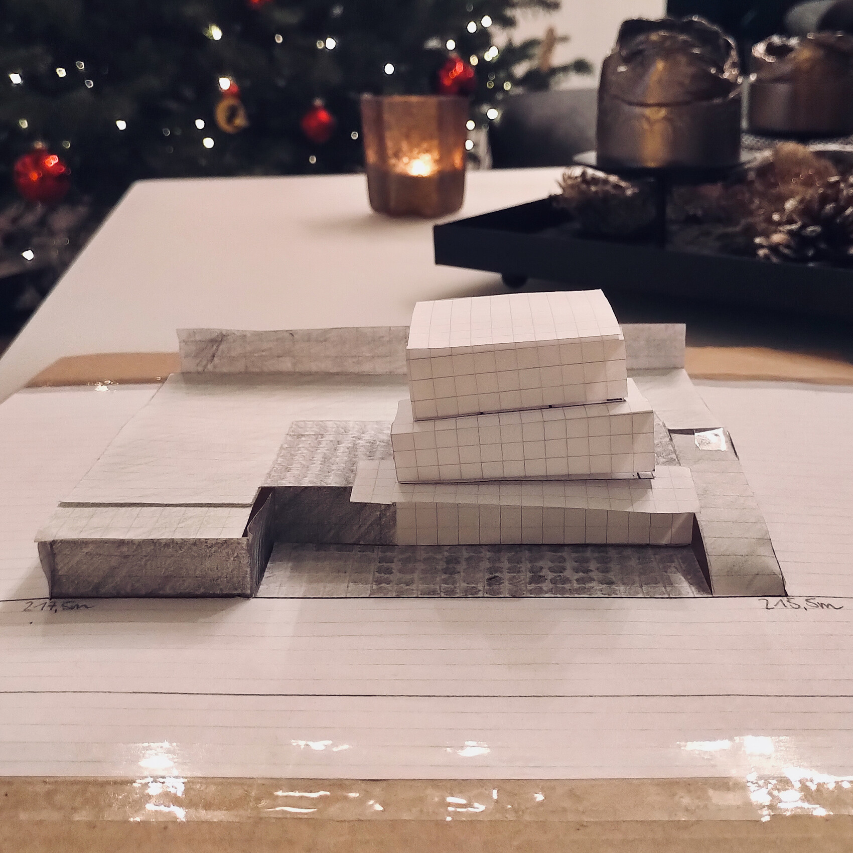 Papiermodell aus kariertem Rasterpapier, dreistufige Pyramide auf Notizblatt.
