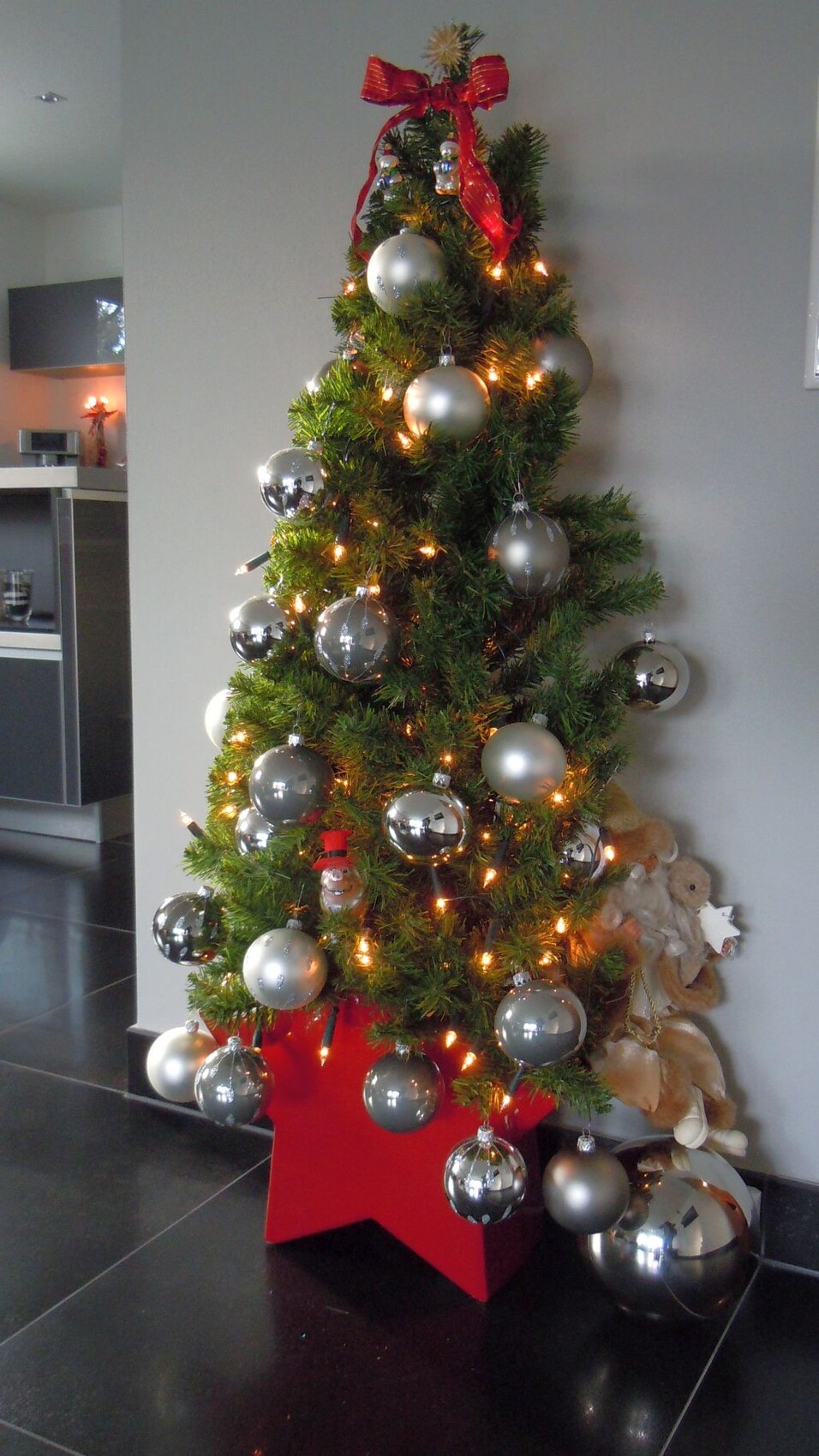 Weihnachtsbaum im modernen Wohnzimmer mit silbernen Kugeln und Lichterkette