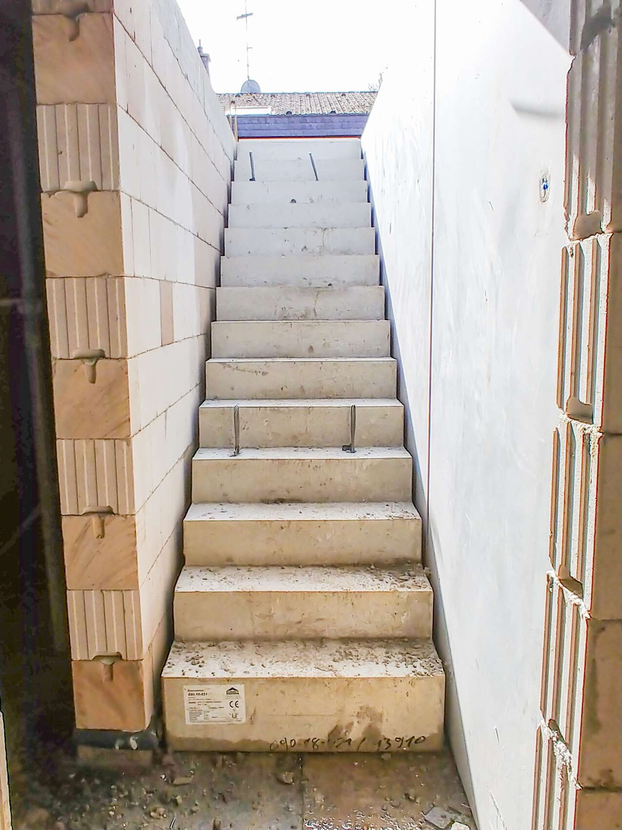Weiße Betontreppe zwischen zwei Wänden im Außenbereich, Blick nach oben.