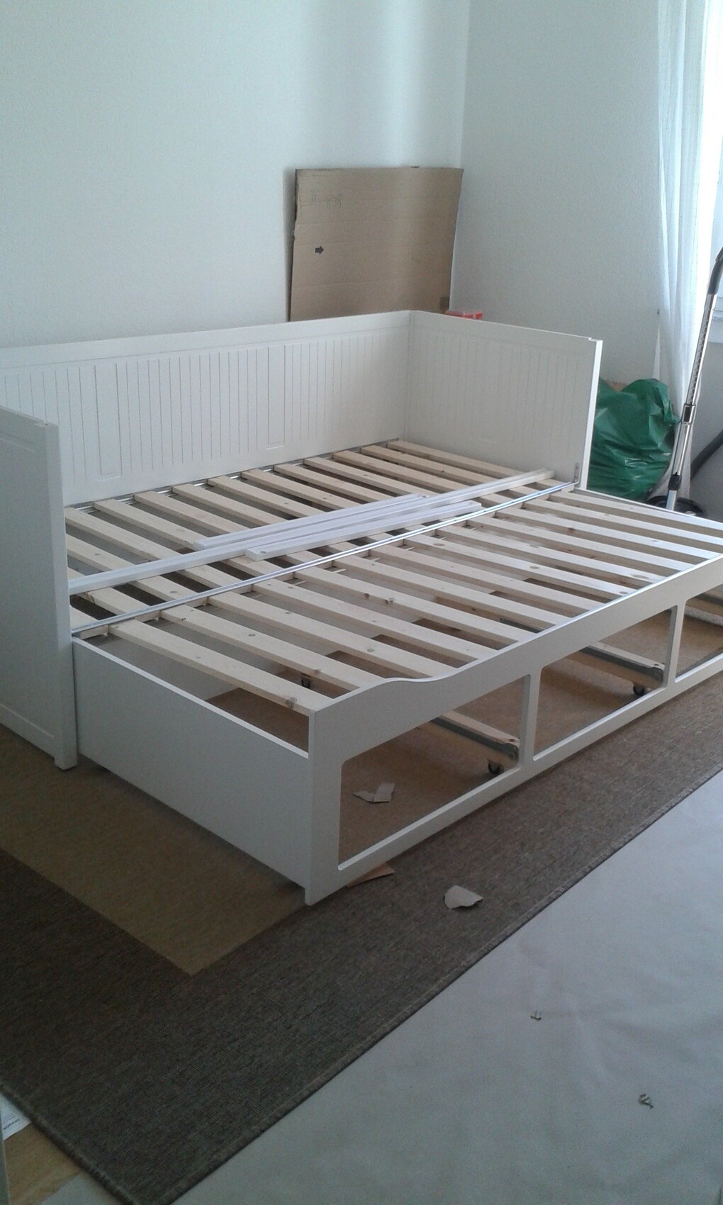 Weißes Bettgestell mit Lattenrost im Schlafzimmer, Aufbauphase.