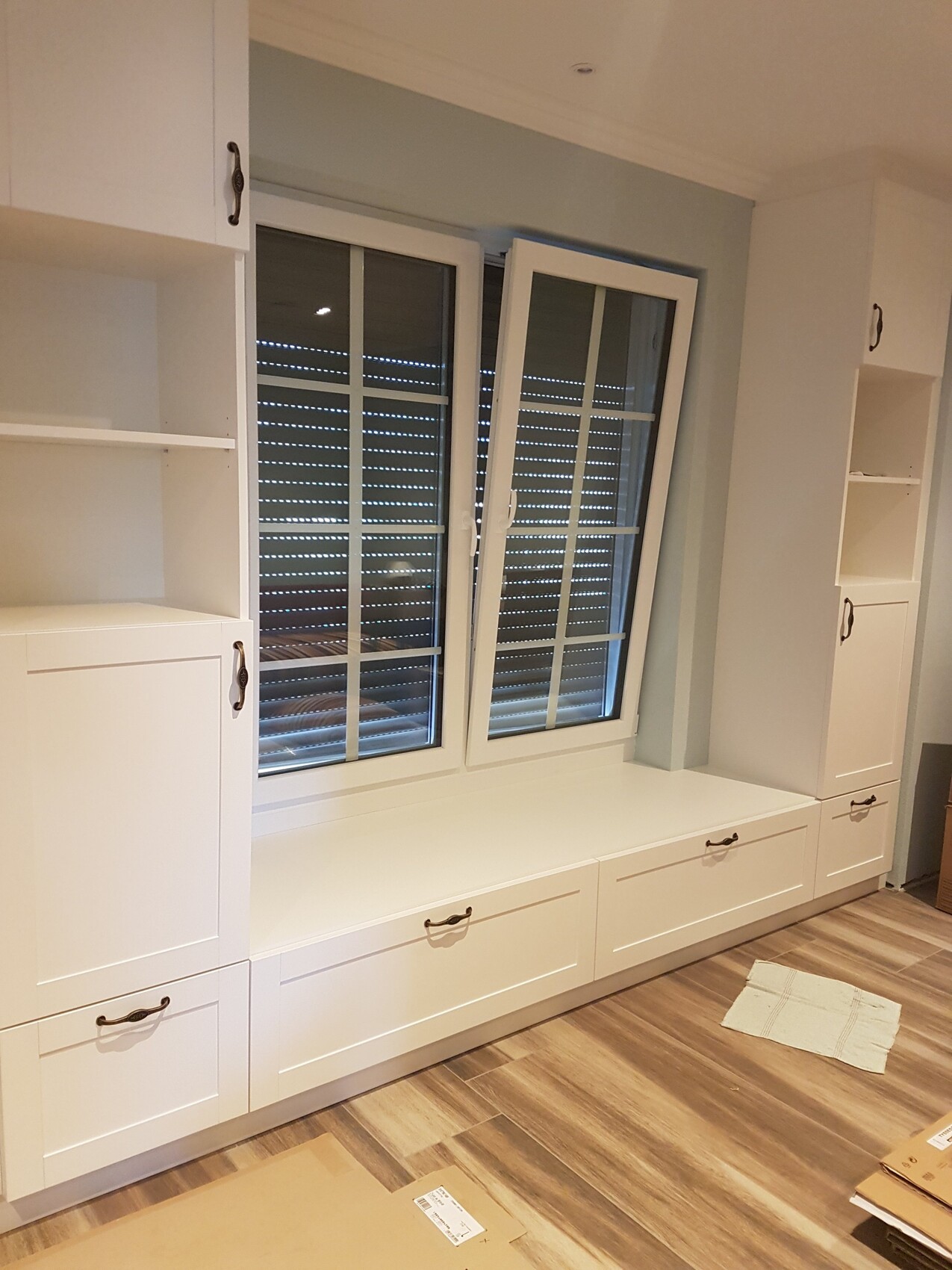 Weisse Einbau-Schränke mit Fensterbank um Fenster mit Rollladen, Wohnraum, Holzboden