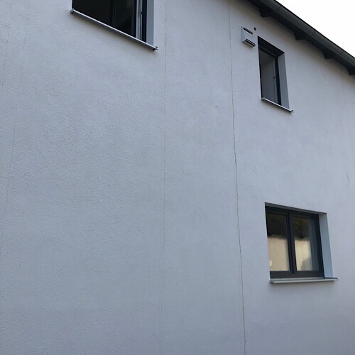 Weiße Hausfassade mit zwei Fenstern, Außenwanddetail