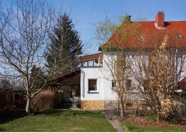 Einfamilienhaus mit rotem Ziegeldach, weiße Fassade, Garten.