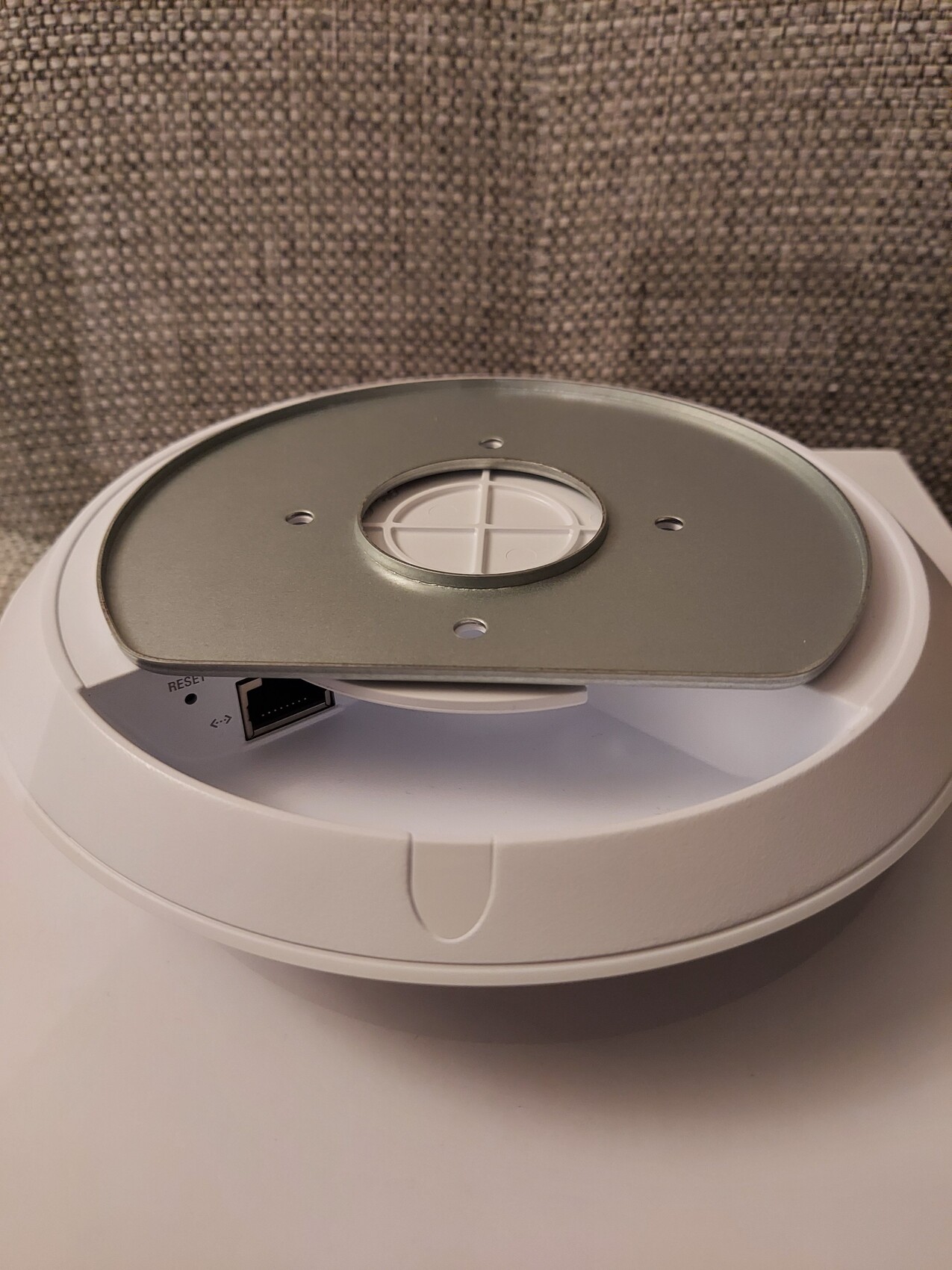 Runder weißer Smart-Home-Hub mit silbernem Deckel, zentralem Kreuzknopf und seitlichem Ethernet-Port