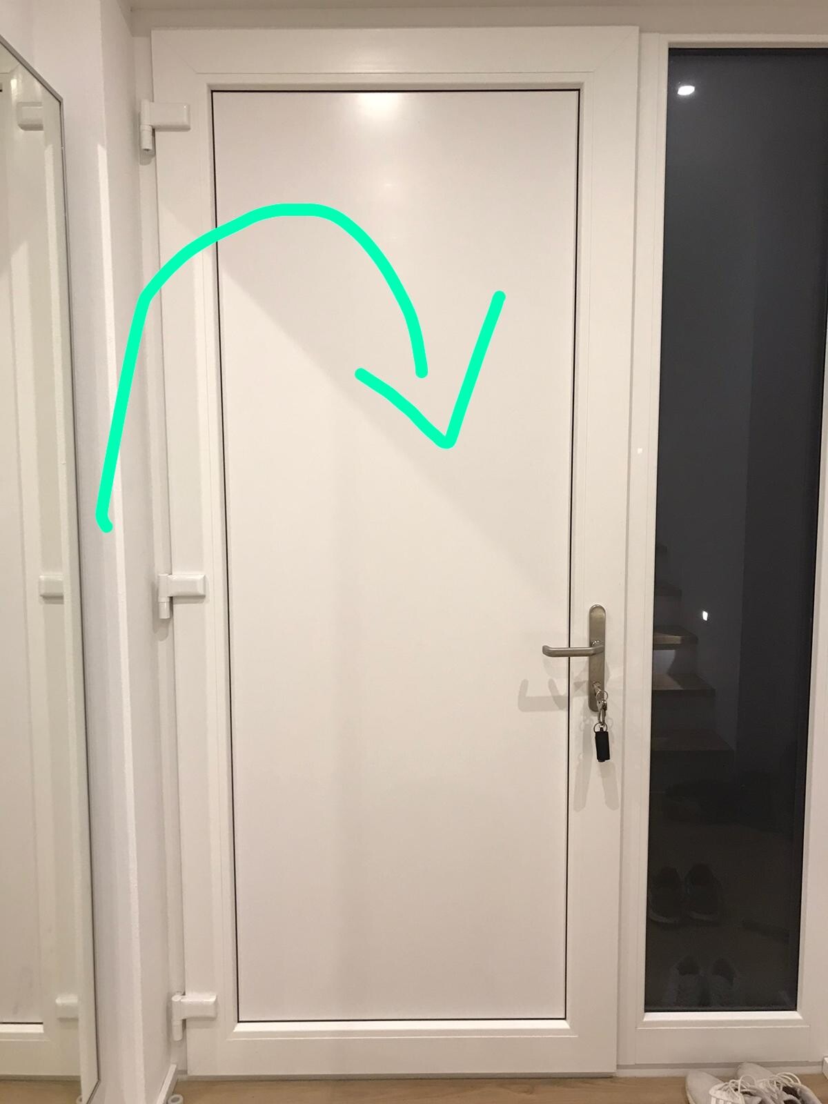 Weiße Tür mit grün gezeichnetem Pfeil; Griff rechts mit Schlüsselanhänger; Glasfenster rechts zeigt Treppen.