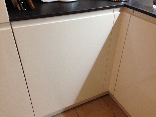 Unterer weißer Küchenschrank mit schwarzer Arbeitsplatte; diagonal verlaufender Schatten.