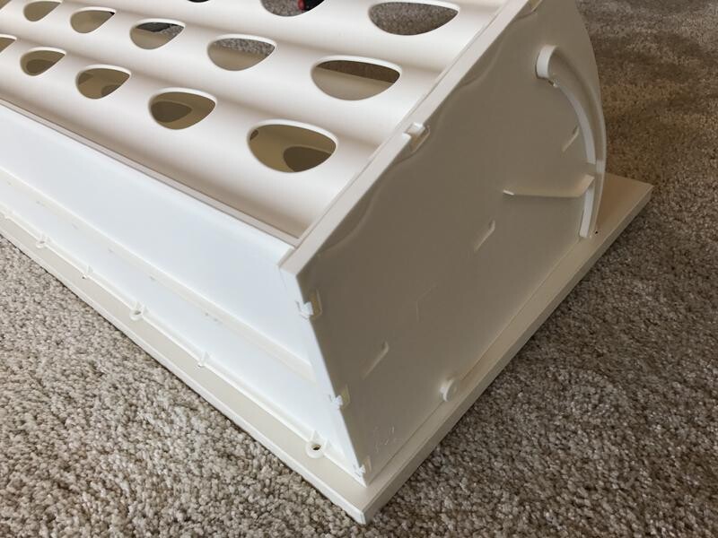 Weißer Brutkasten/Eierbrüter mit runden Fächern auf Teppichboden.