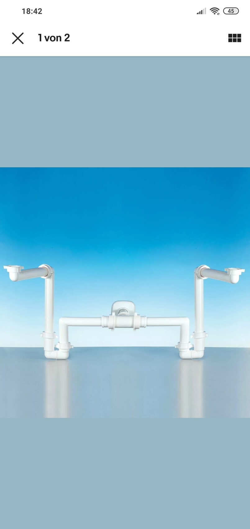 Weißes PVC-Rohrsystem mit horizontaler Brücke und zentralem Ventil vor blauem Hintergrund.