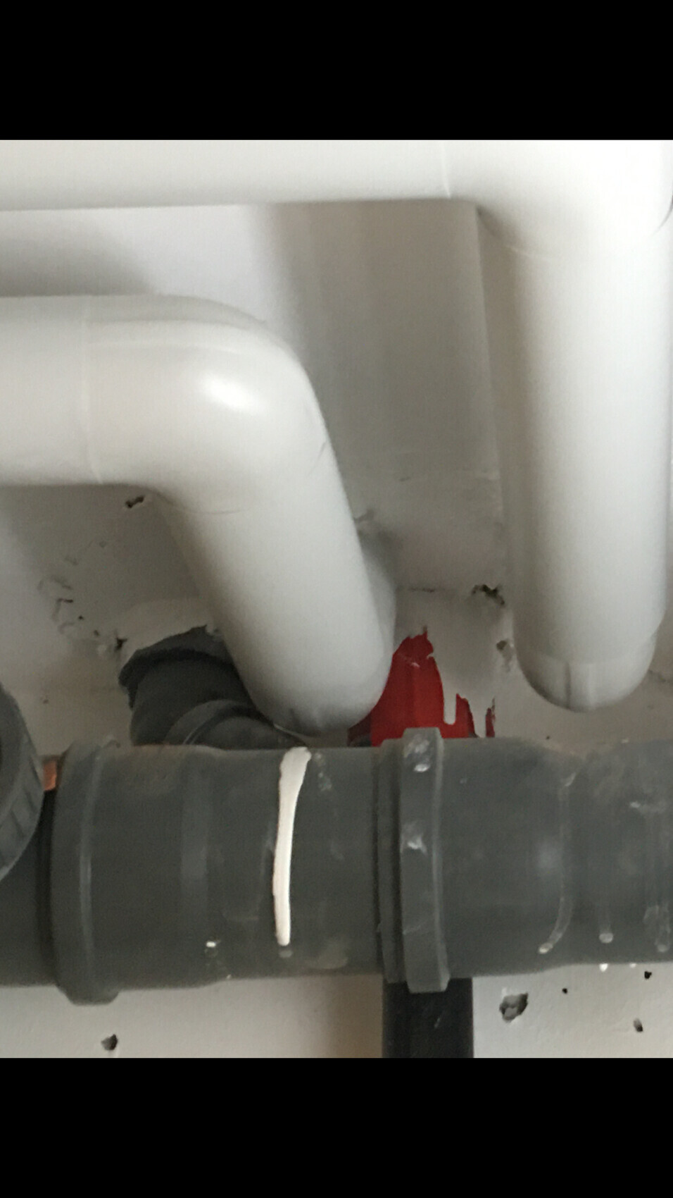 Unter dem Spülbecken sichtbare Abflussrohre: weiße U-förmige Leitung und graue PVC-Rohre.