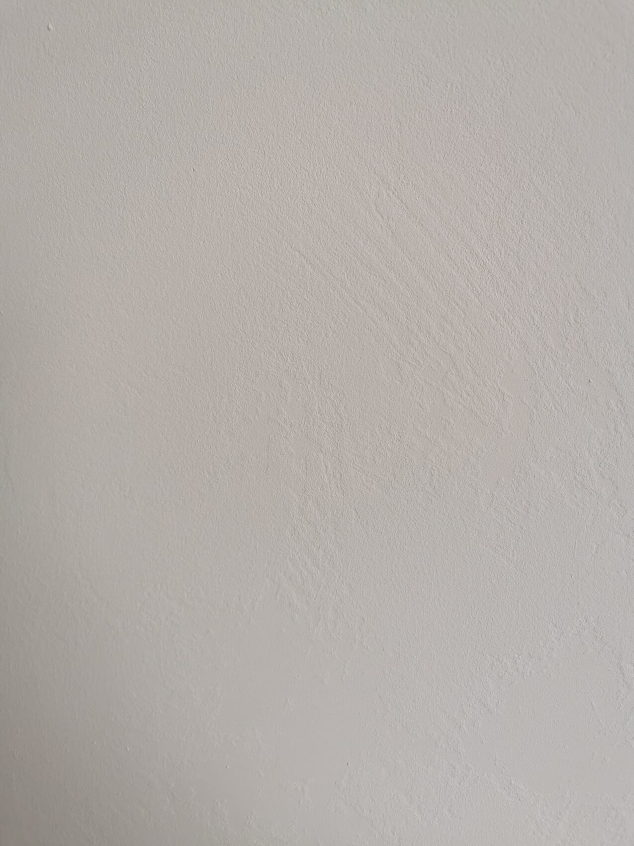 Beige Wand mit feiner, unregelmäßiger Putztextur.