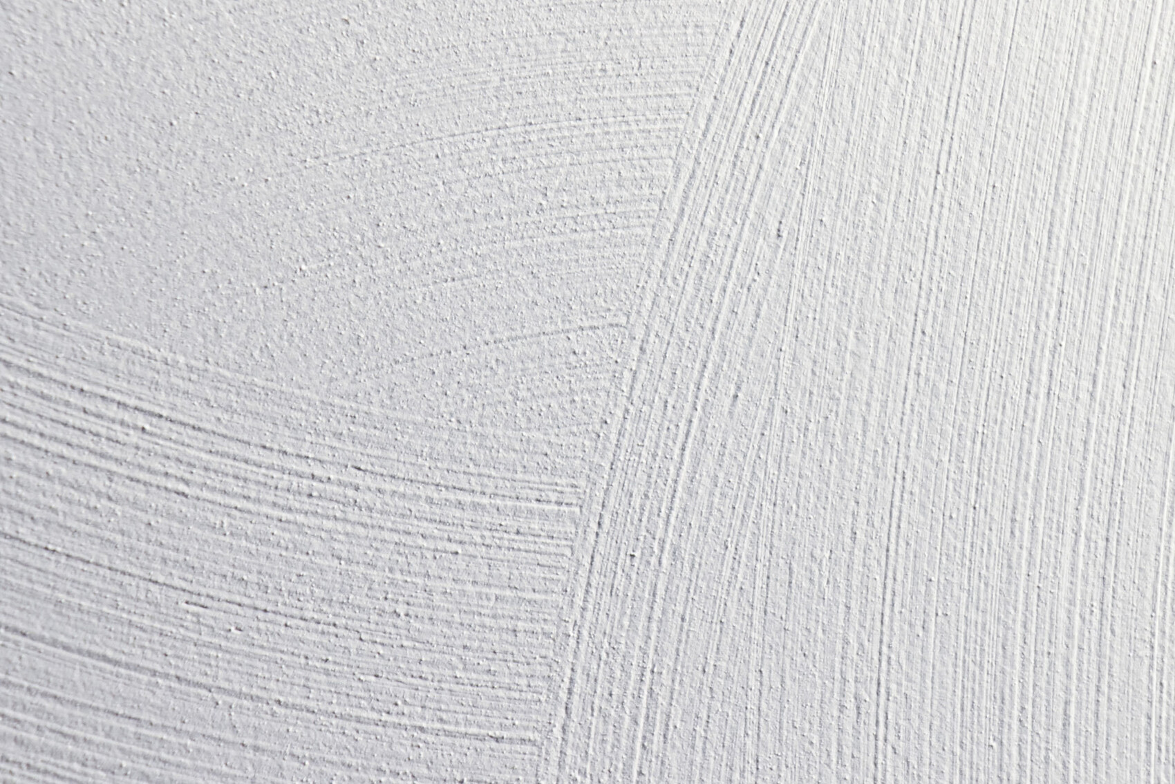 Nahaufnahme einer weißen Putzoberfläche mit sichtbaren Texturen und Strichen.