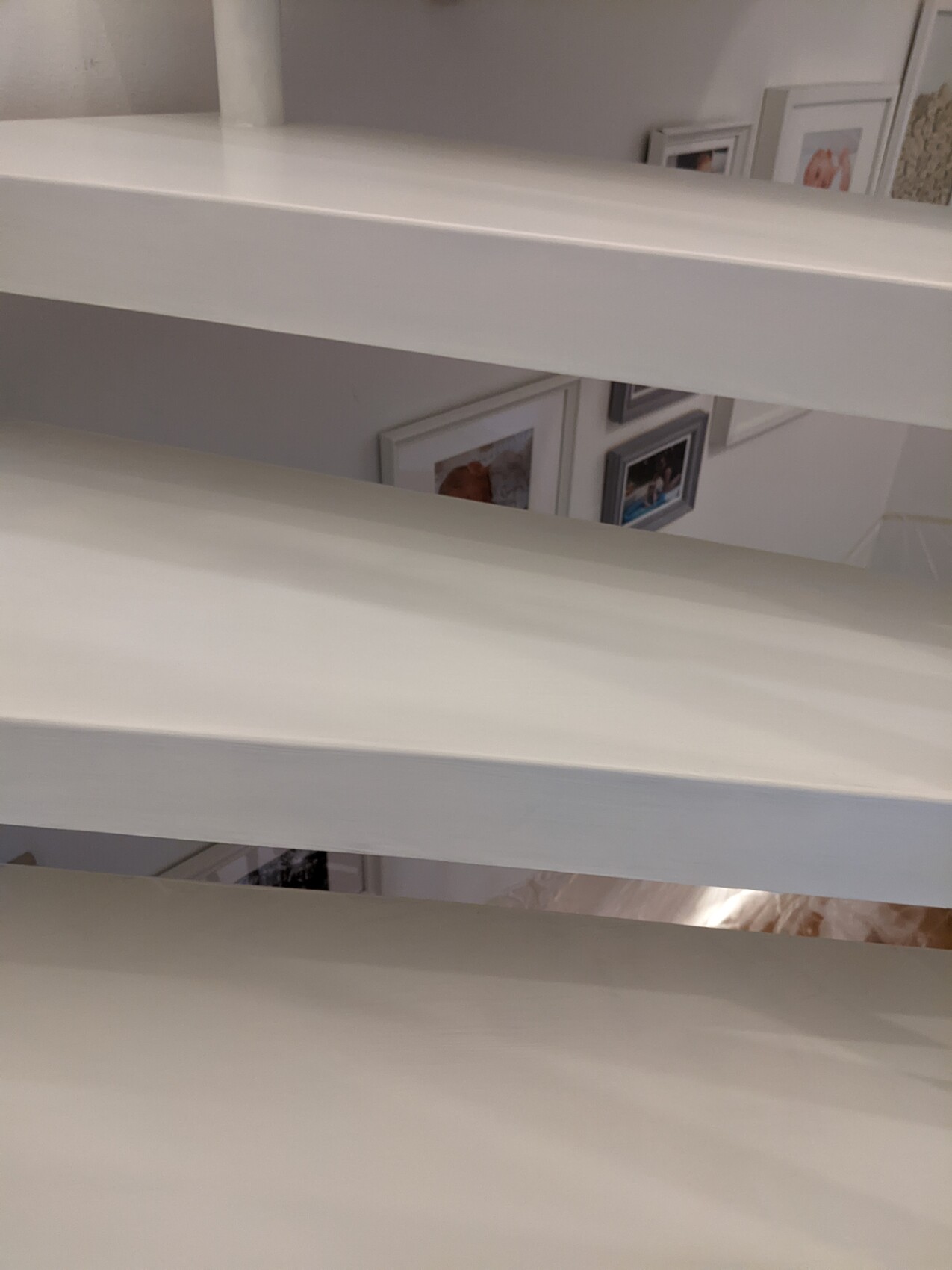 Weiße horizontale Treppenstufen eines modernen Treppendesigns; dahinter Bilderrahmen an der Wand.