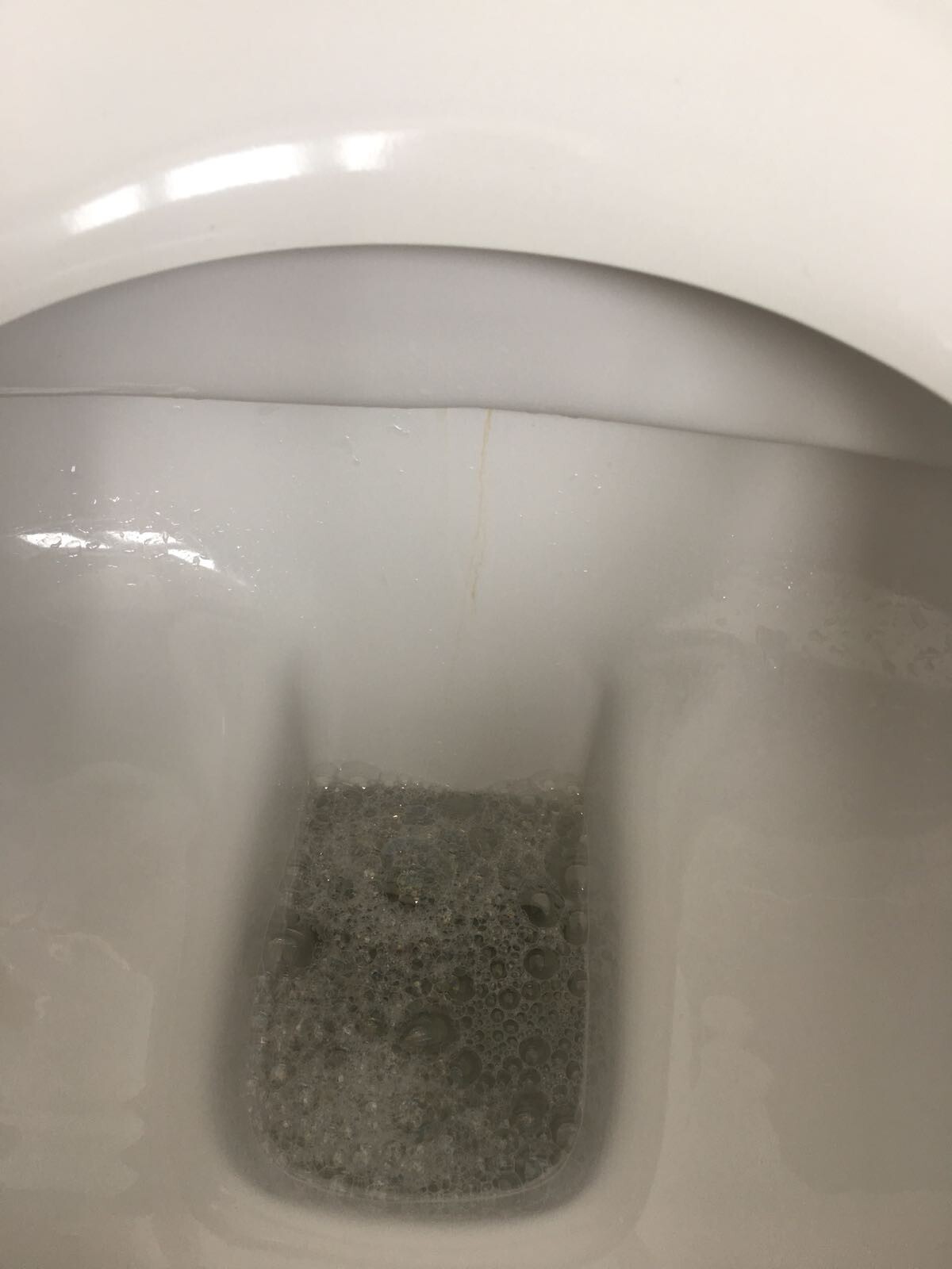 Weiße Toilette mit schaumigem Wasser im Becken
