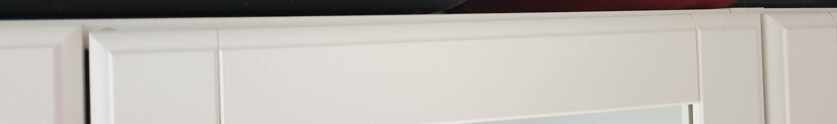 Weißer Schrank mit rahmigen Türen und darunter Spiegelglas.